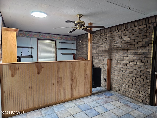 kitchen with ceiling fan and brick wall