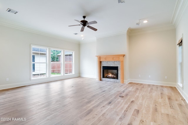 unfurnished living room featuring ceiling fan, light hardwood / wood-style flooring, a tiled fireplace, and crown molding