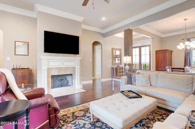 living room with ceiling fan with notable chandelier, a fireplace, ornamental molding, and dark hardwood / wood-style flooring