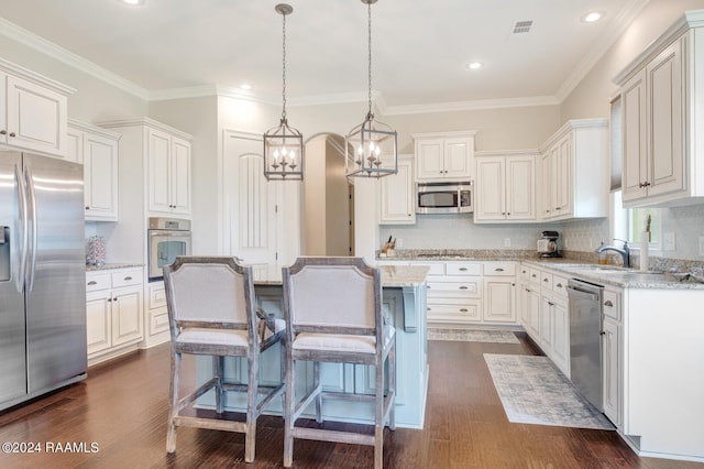 kitchen with appliances with stainless steel finishes, a kitchen island, a chandelier, and white cabinetry