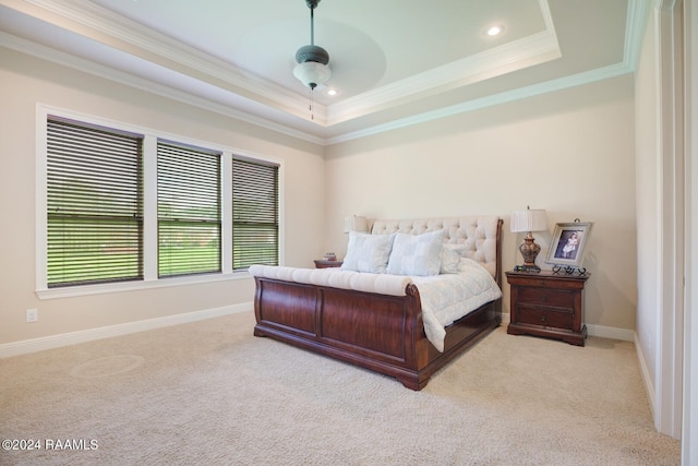 bedroom with ceiling fan, light colored carpet, a tray ceiling, and crown molding