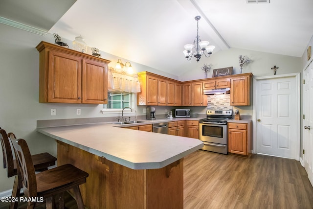 kitchen featuring stainless steel appliances, sink, kitchen peninsula, and decorative light fixtures