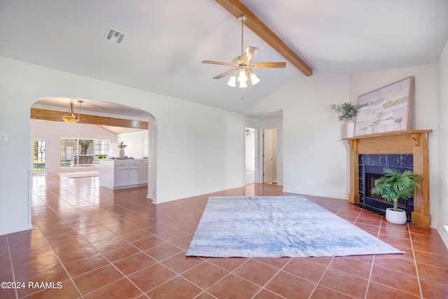 unfurnished living room with a tile fireplace, lofted ceiling with beams, ceiling fan, and dark tile patterned flooring