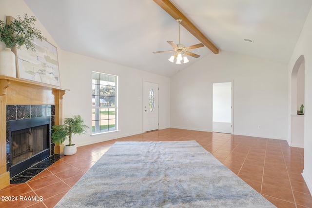 interior space with ceiling fan, tile patterned floors, lofted ceiling with beams, and a tile fireplace