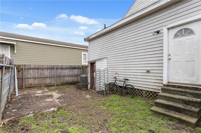 view of yard with entry steps, central air condition unit, and fence