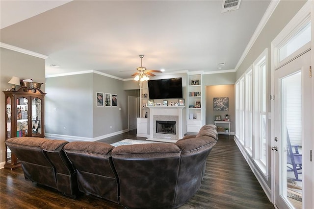 living room with dark wood-type flooring, a fireplace with flush hearth, visible vents, baseboards, and ornamental molding