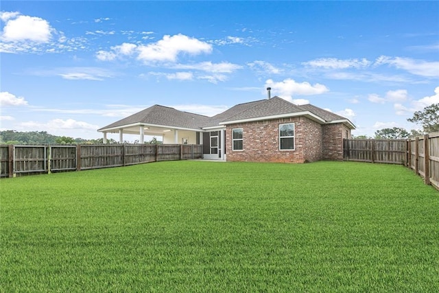 back of property featuring brick siding, a lawn, and a fenced backyard