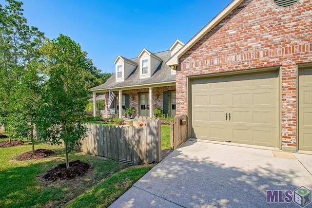 view of front of property featuring brick siding, driveway, an attached garage, and fence