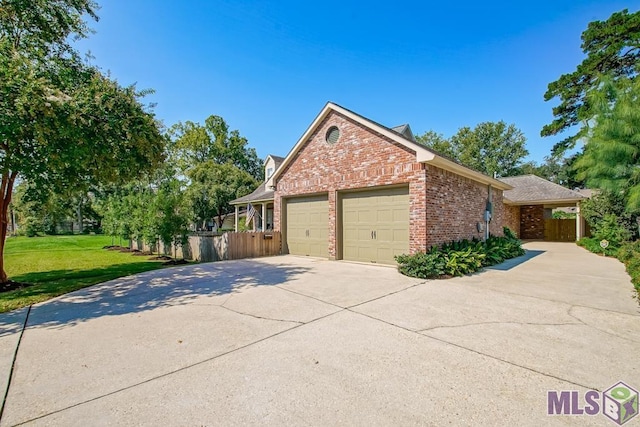 view of side of property featuring brick siding, a yard, concrete driveway, an attached garage, and fence