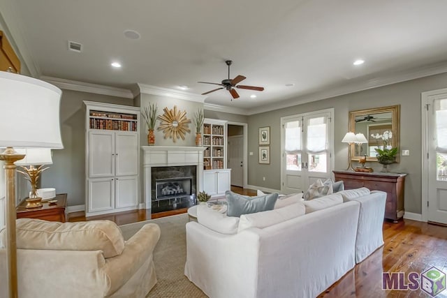 living room featuring light wood-type flooring, visible vents, crown molding, and a premium fireplace