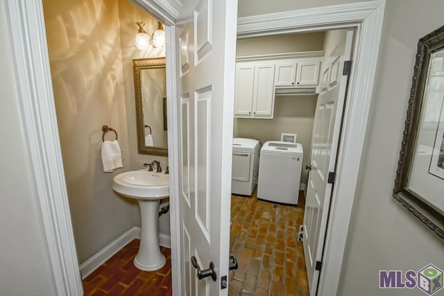 half bath featuring brick floor, washing machine and dryer, and baseboards