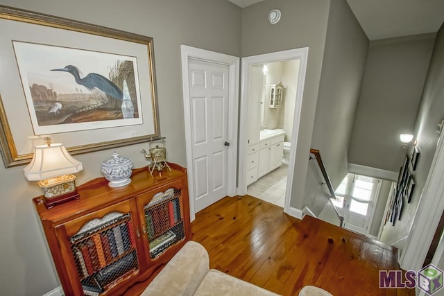 hall with hardwood / wood-style floors, an upstairs landing, and baseboards