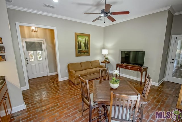 dining room with visible vents, baseboards, a ceiling fan, brick floor, and crown molding