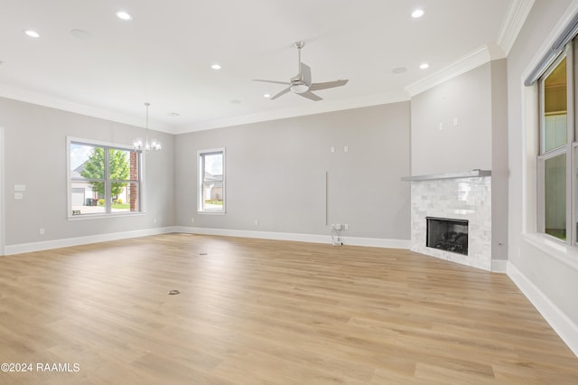 unfurnished living room with ceiling fan with notable chandelier, light wood-type flooring, and crown molding