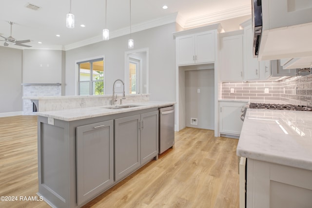 kitchen with hanging light fixtures, ceiling fan, stainless steel dishwasher, a kitchen island with sink, and sink