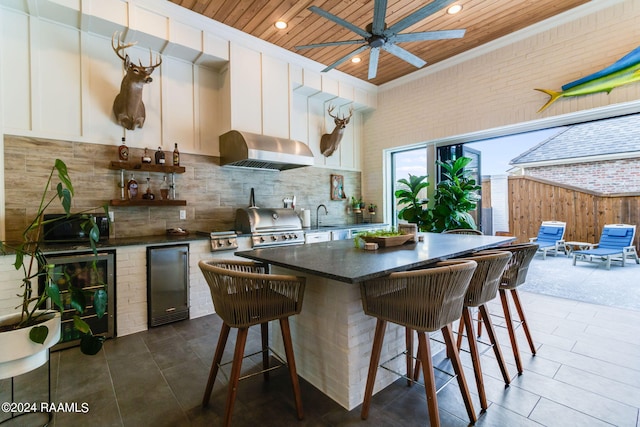 kitchen with ceiling fan, white cabinets, wood ceiling, stainless steel fridge, and exhaust hood