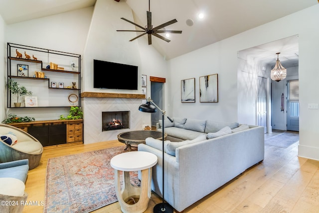 living room with high vaulted ceiling, light wood-type flooring, a high end fireplace, and ceiling fan