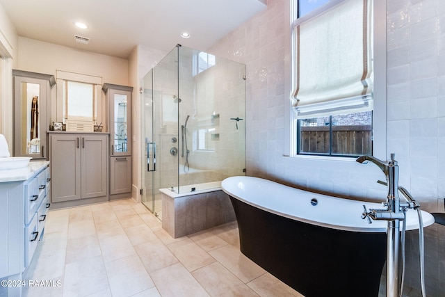 bathroom with independent shower and bath, vanity, tile walls, and tile patterned floors