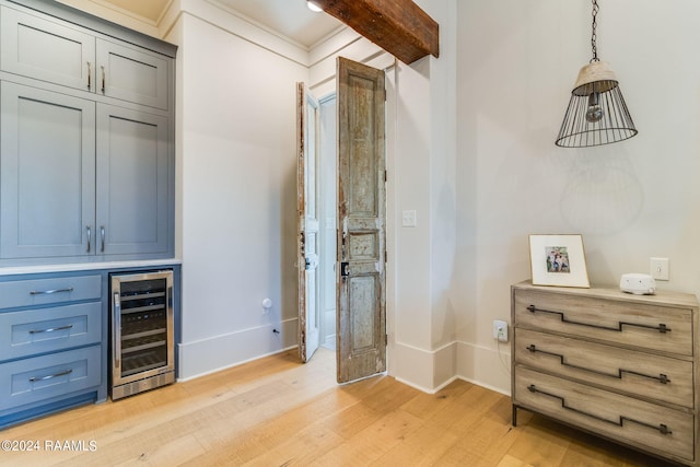 interior space with crown molding, beverage cooler, light hardwood / wood-style flooring, and decorative light fixtures