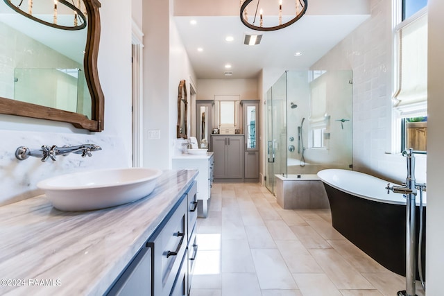 bathroom with vanity, a notable chandelier, tile patterned floors, shower with separate bathtub, and tile walls