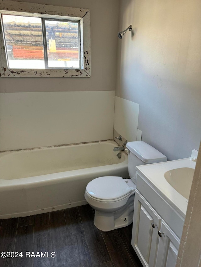 bathroom with wood-type flooring, a tub to relax in, vanity, and toilet