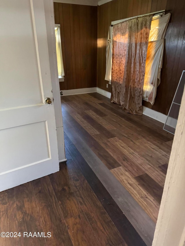 unfurnished room featuring wooden walls and dark wood-type flooring