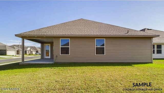 rear view of house with a lawn and roof with shingles