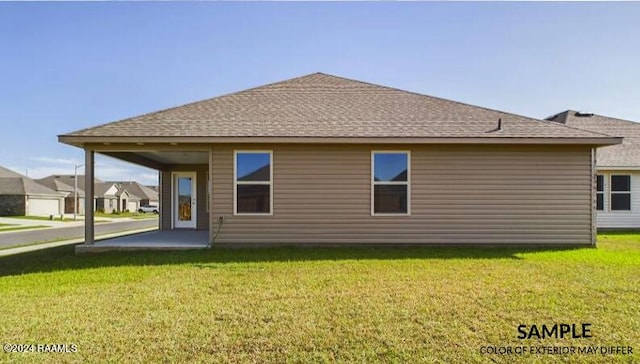rear view of property with roof with shingles and a yard