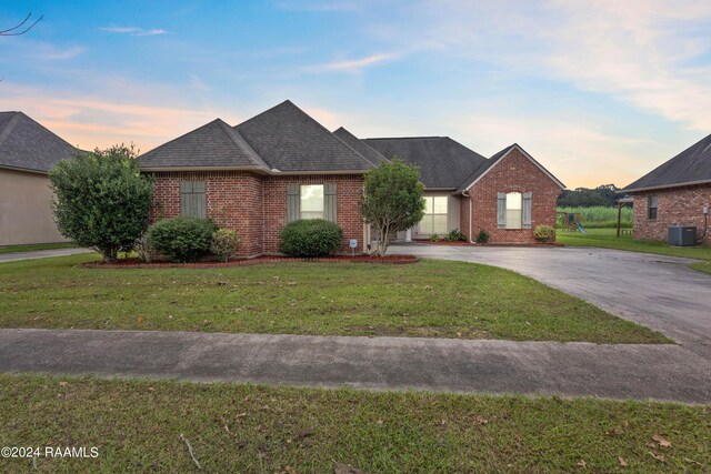 single story home with central AC unit and a yard