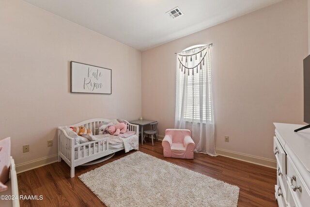 bedroom with a nursery area and dark wood-type flooring