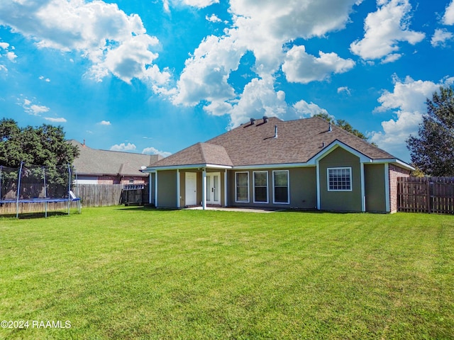 back of property featuring a patio area, a lawn, and a trampoline