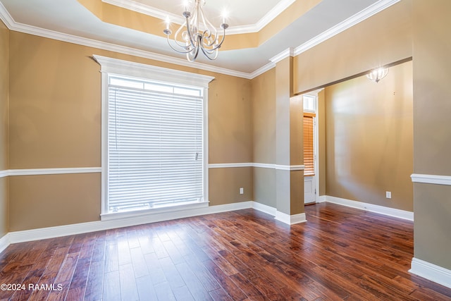 spare room featuring a notable chandelier, ornamental molding, a tray ceiling, and dark hardwood / wood-style flooring