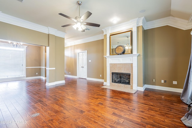 unfurnished living room with crown molding, a fireplace, dark hardwood / wood-style floors, and ceiling fan with notable chandelier