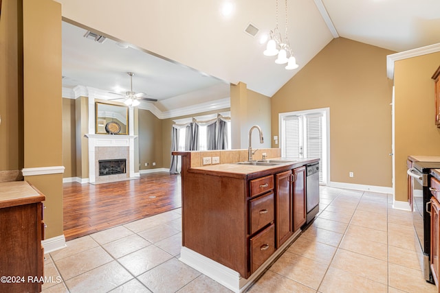 kitchen featuring appliances with stainless steel finishes, sink, light wood-type flooring, hanging light fixtures, and a kitchen island with sink