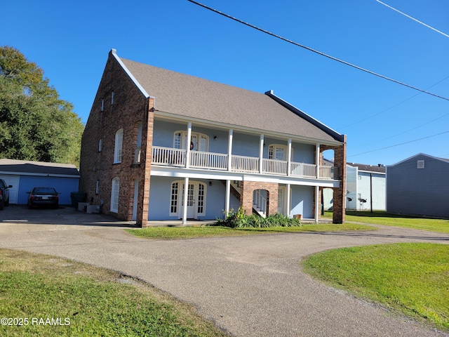 view of front facade featuring french doors, a front yard, and a balcony