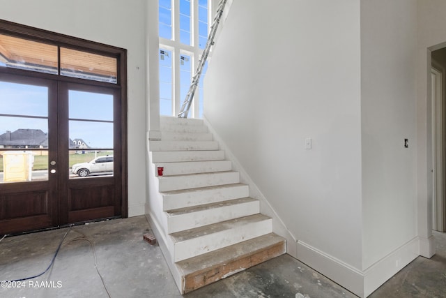 staircase with french doors and concrete flooring