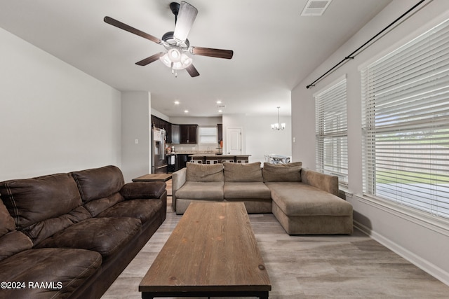 living room featuring ceiling fan with notable chandelier and light hardwood / wood-style floors