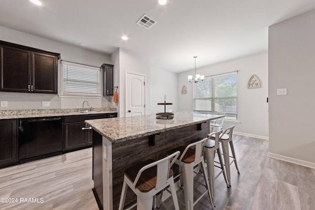 kitchen featuring hanging light fixtures, a notable chandelier, a center island, black dishwasher, and a kitchen bar