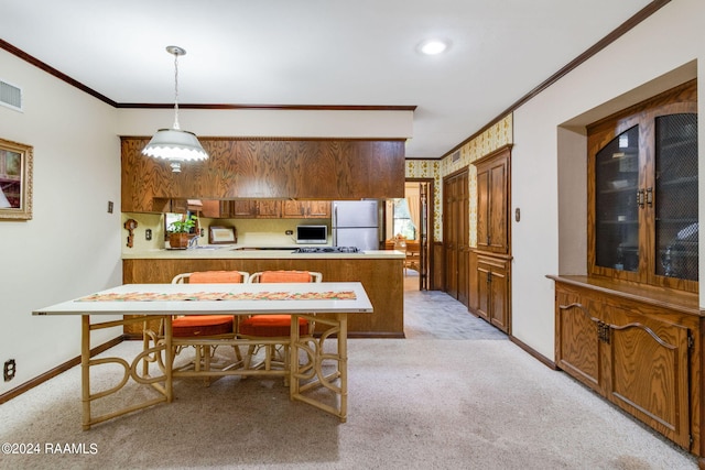 interior space with pendant lighting, ornamental molding, kitchen peninsula, fridge, and light colored carpet