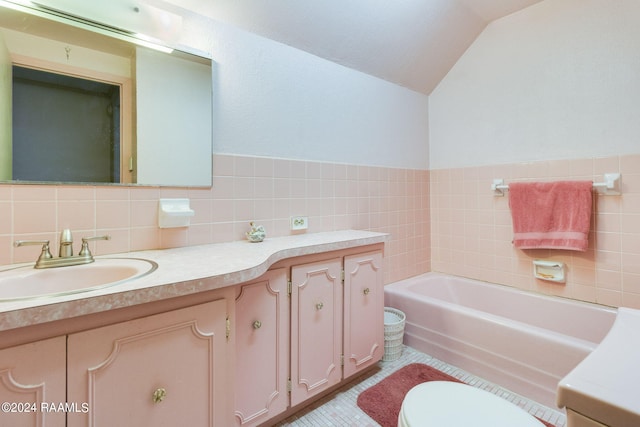 bathroom with tile walls, a bath, vaulted ceiling, vanity, and toilet