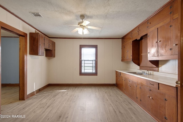 kitchen with light hardwood / wood-style floors, crown molding, ceiling fan, and sink