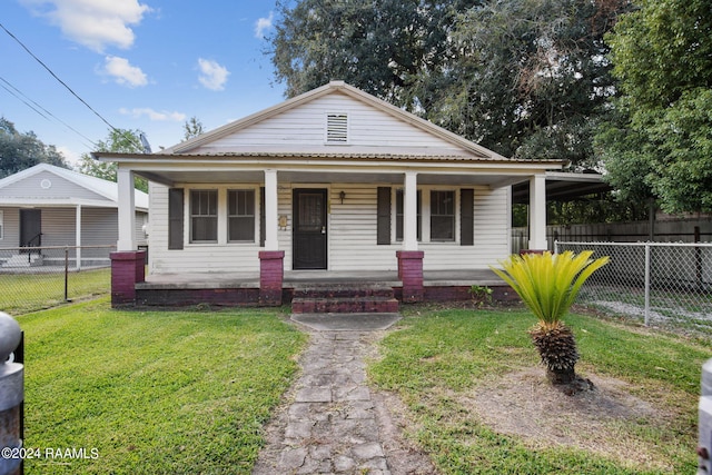 bungalow featuring covered porch and a front yard