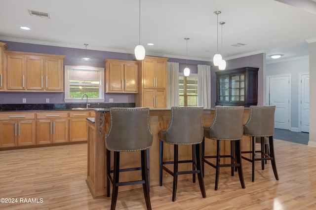 kitchen featuring light wood-type flooring, crown molding, pendant lighting, and a wealth of natural light