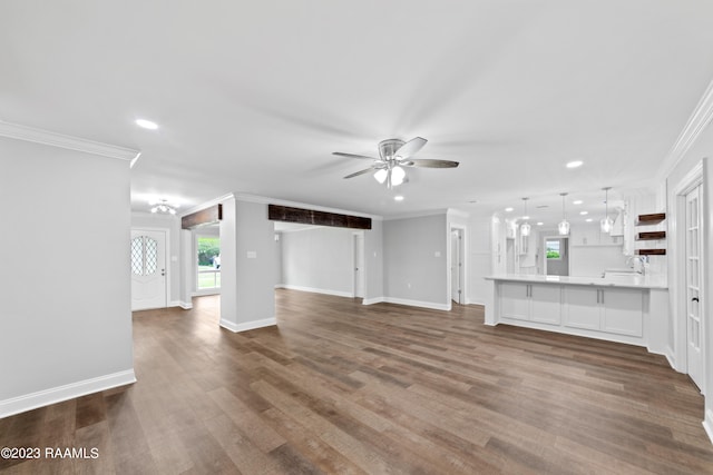 unfurnished living room featuring ceiling fan, sink, crown molding, and dark hardwood / wood-style flooring