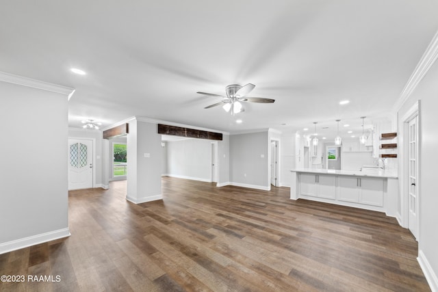 unfurnished living room with ceiling fan, sink, dark hardwood / wood-style floors, and ornamental molding