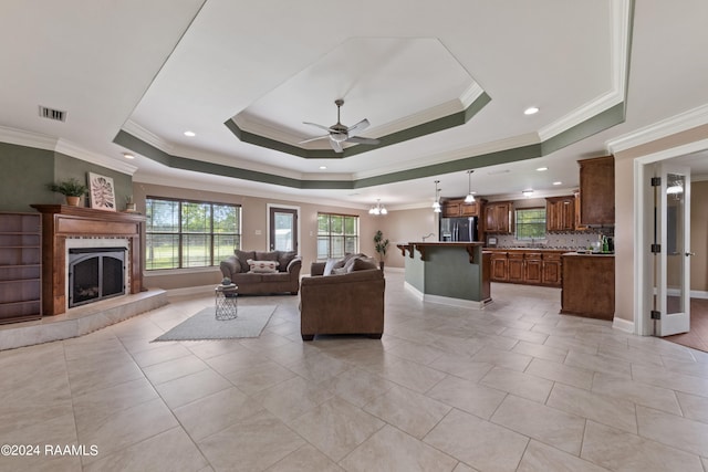 tiled living room featuring ornamental molding, a tray ceiling, and ceiling fan