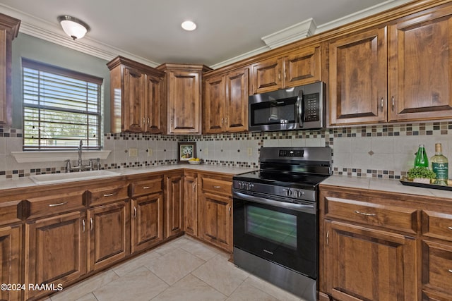 kitchen featuring appliances with stainless steel finishes, tasteful backsplash, light tile patterned floors, ornamental molding, and sink