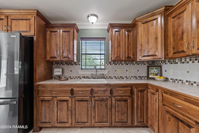 kitchen featuring stainless steel refrigerator, decorative backsplash, light tile patterned flooring, and sink