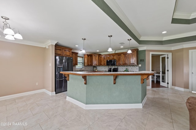 kitchen featuring hanging light fixtures, a center island with sink, crown molding, a kitchen bar, and fridge with ice dispenser