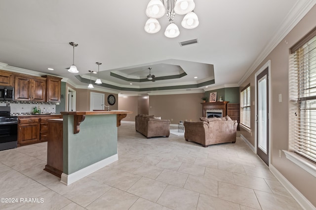 kitchen featuring appliances with stainless steel finishes, ceiling fan with notable chandelier, pendant lighting, a kitchen bar, and ornamental molding